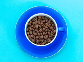 cup full of coffee beans on blue background