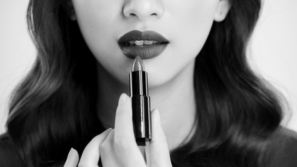 Detail of a beautiful woman applying lipstick