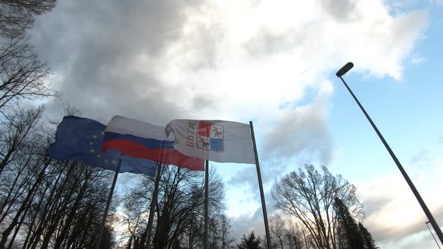 European, Slovenian and State Protocol Services of Slovenia flags waving in wind. Slow motion, looking up