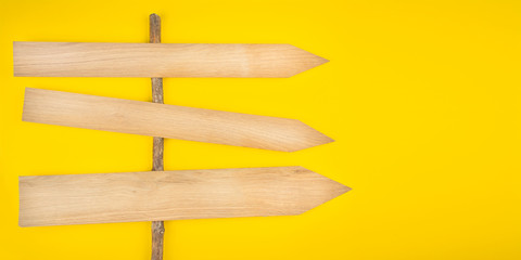 Wooden signpost on a yellow background. Wooden arrows. Banner. Copy space.