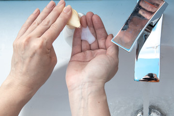 Top above close up view woman standing in bathroom washing her hands under flowing water flushing soap. Stop corona virus covid19, keep personal hygiene, infectious pandemic disease prevention concept