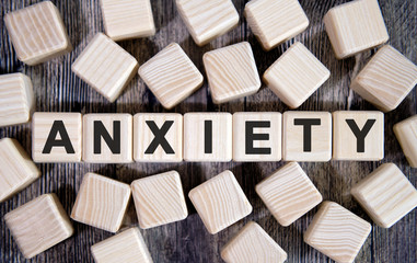 ANXIETY - medical concept, text on wooden cubes and many cubes around on a dark background