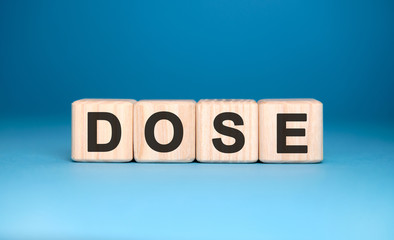 DOSE - text on wooden blocks, medical concept, blue background