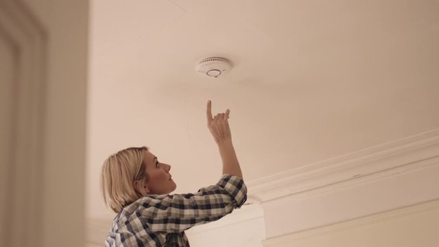 Adult Woman installing smoke detector in home