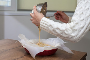 The hostess prepares apple charlotte at home in the kitchen and pours the dough into a baking dish