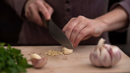 Close-up of the hands of a person cutting garlic with a knife