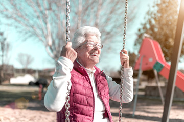 older woman in the park playing swings