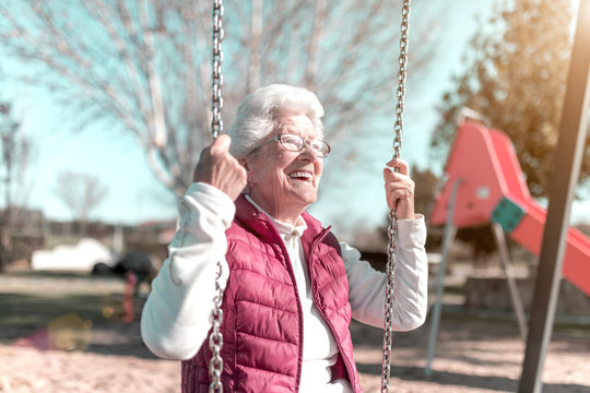 Older Woman In The Park Playing Swings