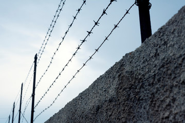 A worn wall with barbed wire on top. A grim symbol of quarantine and social distancing.