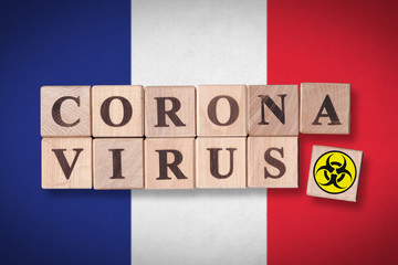 France flag background and wooden blocks with letters spelling CORONAVIRUS and quarantine symbol on it. Novel Coronavirus (2019-nCoV) concept for an outbreak occurs in France.