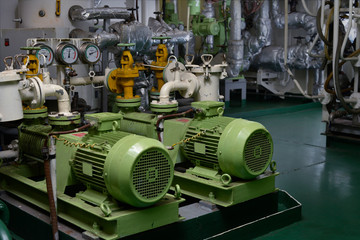Engine room interior of a big ocean going ship with gauges, electrical motors, generators and piping