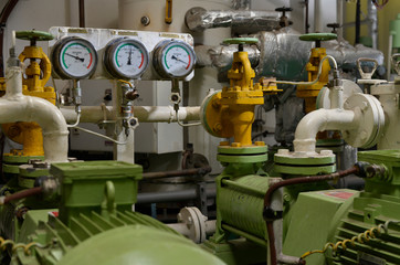 Engine room interior of a big ocean going ship with gauges, electrical motors, generators and piping