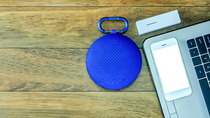Blue bluetooth speaker with smart phone,laptop,power bank on wooden table