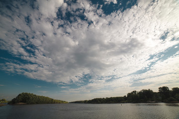 Blue sky with clouds over river during sunset.