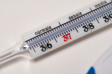 Mercury fever thermometer on white background with Italian writing severity of fever.