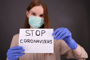 Woman tears sheet of paper with sign "stop coronavirus"