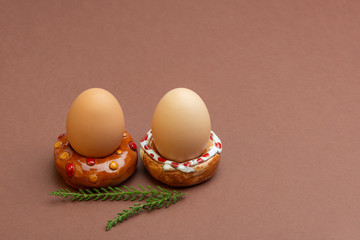 Easter concept. Two donut-shaped handmade ceramic egg holders or cups isolated on brown background. Free space for text