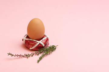 Easter concept. Handmade donut-shaped ceramic egg holder or cup isolated on pink background. Free space for text.