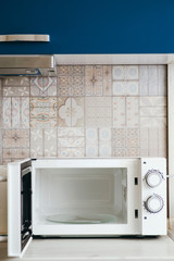 Photo of white open microwave with glass plate in the kitchen.