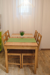 Dining room in a studio, a table with a plant, four chairs and a lamp.