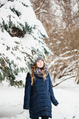 Fototapeta na wymiar A girl of European appearance walks in the Park, forest, winter and snow, dressed in warm clothes, hat, jacket, scarf, rest, Hiking