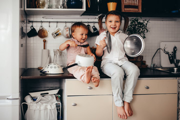 Funny children play music on kitchen tools at home