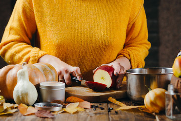 Close-up photo of woman's hands in yellow sweater cutting apples for hot wine. Winter cozy holidays mood.