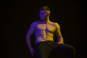 Beautiful male athlete shirtless isolated over black background. Handsome muscular man posing.