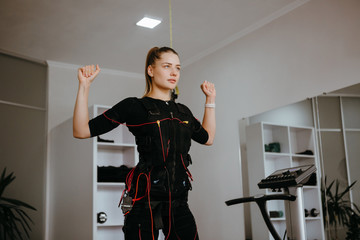Young woman in EMS training suit standing with her arms lifted.