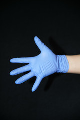  Blue gloved hand outstretched open palm side, on black background
