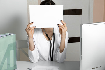 Blank, a piece of paper for text in the hands of a medical officer, doctor in white uniform. Without a face.