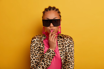 Glamour magnificent ethnic woman wears black sunglasses, has romantic mood, folds lips in mwah,...
