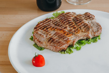 Meat steak and salad with a glass of red wine and cherry tomato on a plate
