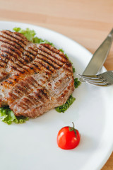 Close-uo of grilled steak with salad and cherry tomato served on a plate