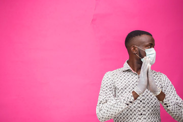 a young african doctor isolated over pink background wearing face mask to prevent, prevented,...