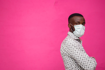 a young african doctor isolated over pink background wearing face mask to prevent himself from the outbreak, disease and flu.