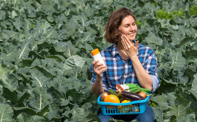woman working on an agricultural field during a sunny day and protecting her skin from the sun with sunscreen. woman holds a basket with collected vegetables on her lap
