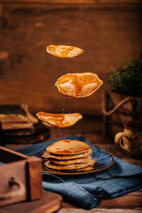 Levitation of fresh baked american pancakes with delicious mapple syrup on old wood table on a blue plate
