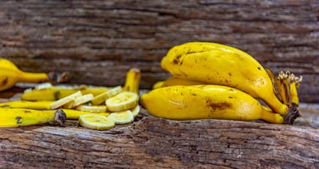 Fresh and sliced bananas on aged wooden background