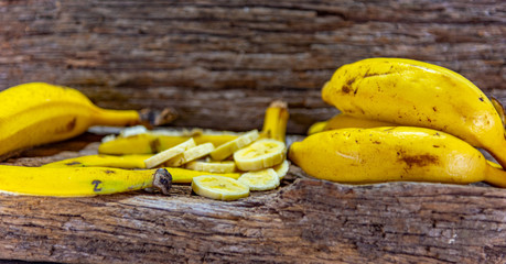 Fresh and sliced bananas on aged wooden background