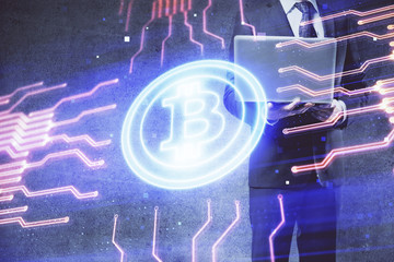 Crypto currency theme hologram with businessman working on computer on background. Concept of...
