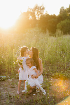 Lifestyle portrait mom and two daughter in happines at the outside in the meadow