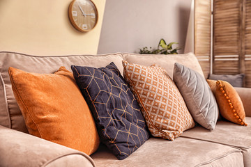 Cushions with pattern, grey and orange on sofa indoors, closeup