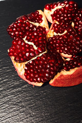 Pomegranate on a dark background. View from above. Pomegranate juice on a dark background. Pieces of pomegranate.