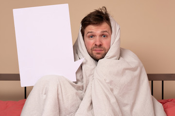 man covering with blanket showing blank billboard sign staying at home alone.