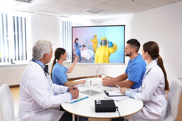 Team of doctors using video projector during coronavirus conference in office