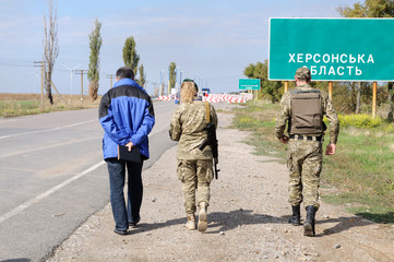 Man and border guards walking, blurred border crossing point Kalanchak on a background, Khersonskaya oblast, Ukraine