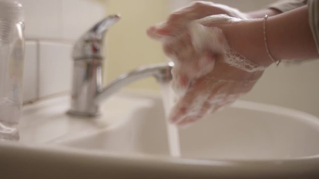 Close-up of a woman washing her hands and rinsing them off in a bathroom sink