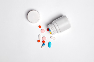 White plastic bottle with medicines and vitamines. tematic health. rose, orange and blue vitamins.