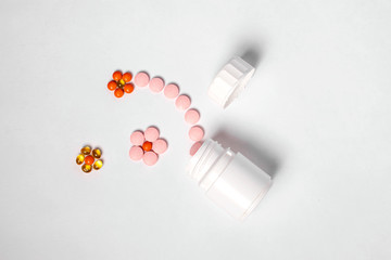 White plastic bottle with medicines and vitamines. tematic health. rose, yellow and red medicines.